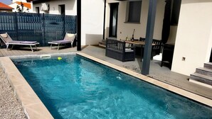 A rectangular swimming pool with a tiled edge, surrounded by a deck area with lounge chairs and a small table. - Villa Rascola Piscine 4 Stars with private pool, Wi-Fi and air conditioning (Le Boulou)