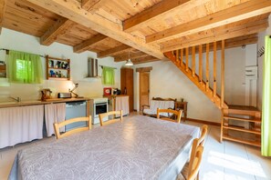 A wooden interior with a dining table, chairs, a kitchen area, and a staircase.
