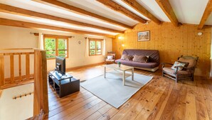 A wooden interior with a sofa, chairs, a TV, and a window. - Holiday Home 'La Petite Palasse' with Private Pool, Wi-Fi & Air Conditioning (LE THOR)