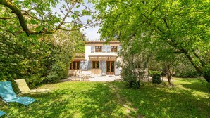 A two-story house with a garden, a patio with chairs, and a small table. - Holiday Home 'La Petite Palasse' with Private Pool, Wi-Fi & Air Conditioning (LE THOR)