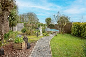 Un giardino con un vialetto in ghiaia, una recinzione in legno e una statua.