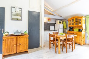 Une cuisine compacte avec un coin repas, des meubles en bois et un petit réfrigérateur.