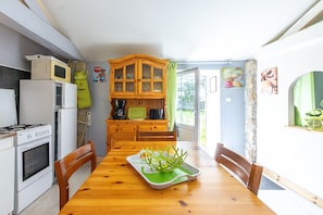 Une cuisine avec une table en bois, des chaises, un four à micro-ondes, un réfrigérateur et un placard.