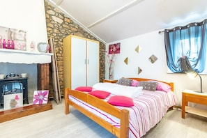 Une chambre à coucher avec un lit, une armoire, une cheminée et une table de chevet.