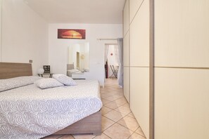 Un dormitorio con cama, mesita de noche, espejo y puerta que da a un baño.