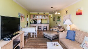 Un espacio habitable pequeño con televisor, mesa de comedor y kitchenette.