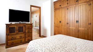 Ein Schlafzimmer mit einem Bett, einem Holzschrank und einem Fernseher auf einer Kommode.