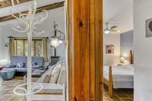 Une pièce comprenant un lit, un canapé, une porte en bois, un ventilateur de plafond et une fenêtre.