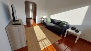A living room with a sofa, a coffee table, a TV, and a rug.