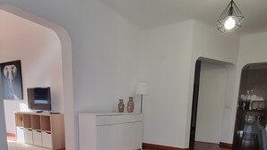 A spacious living area with a tiled floor, a white entertainment unit, and a modern pendant light.