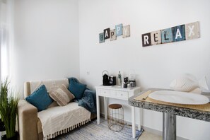 Ein gemütliches Zimmer mit einem weißen Sofa, einem kleinen weißen Tisch und einer Wand mit der Aufschrift 'HAPPY RELAX'.