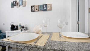 Een aanrecht met twee borden, een mes en twee wijnglazen op placemats, met een bordje 'HAPPY RELAX' erboven.