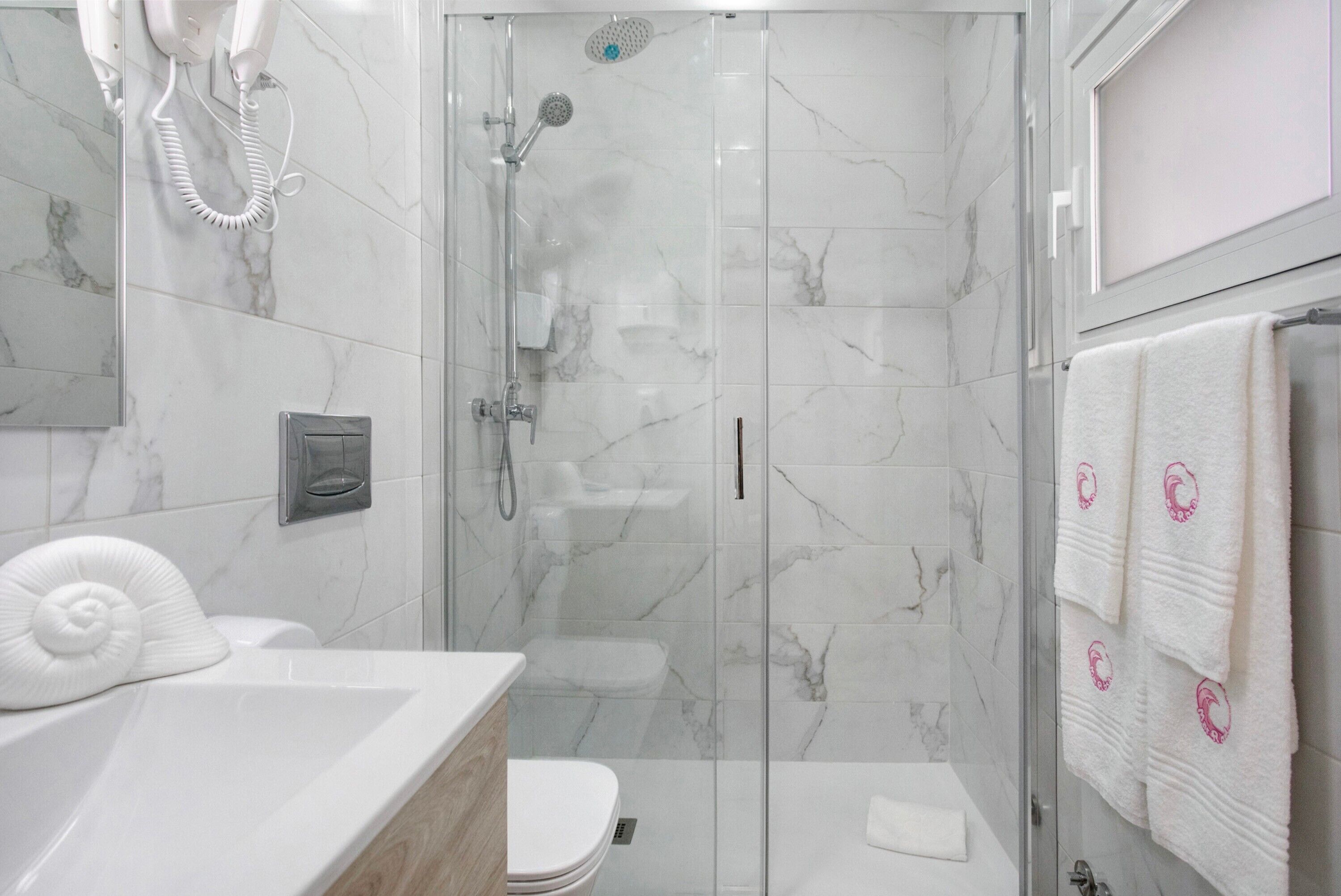 Ein modernes Badezimmer mit einer einteiligen Duschkabine, Toilette und Waschbecken mit Handtuchhalter.