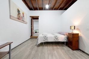 Une chambre à coucher avec un lit, une armoire en bois, un bureau et un tableau accroché au mur.