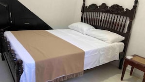 Una cama individual con cabecera de madera y colcha color beige.