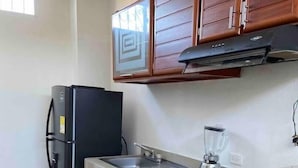 Una cocina con armarios de madera, un refrigerador negro, una estufa a gas y un lavamanos.