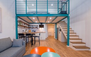 Een modern appartement met een keuken, eethoek en een trap naar een vide.