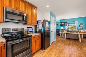 A kitchen with wooden cabinets, a stainless steel stove, a black refrigerator, and a microwave.