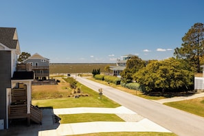 A residential street with houses, a clear sky, and a view of the water.