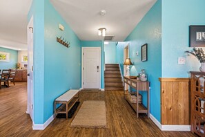 Un pasillo con un banco de madera, una alfombra, una escalera y una consola decorada con objetos.