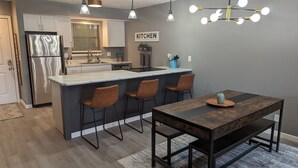 A modern kitchen with a central island, bar stools, a dining table, and pendant lighting. - Ozark Overlook~Backyard~Pointe Royale Resort~Pools/Hottub (Branson)