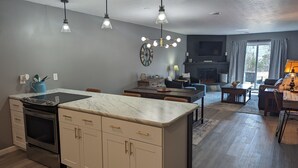 A modern kitchen with a central island, a dining area with a fireplace, and a living room with a TV and seating. - Ozark Overlook~Backyard~Pointe Royale Resort~Pools/Hottub (Branson)