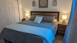 A bedroom with a wooden headboard, a bed with a blue patterned bedspread, two bedside tables with lamps, and decorative wall art. - Ozark Overlook~Backyard~Pointe Royale Resort~Pools/Hottub (Branson)