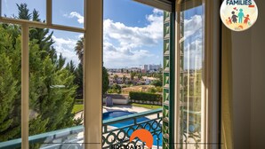 Un balcón con piscina, árboles y vistas a un paisaje urbano.
