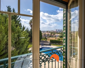 Un balcon avec une piscine, des arbres et une vue sur le paysage urbain.