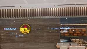A restaurant interior with a modern design, featuring a wooden wall and a sign for 'KUYA J RESTAURANT'. - HEL CONDOTEL at SMDC GRACE RESIDENCES (Makati)