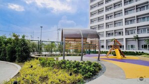 A playground area with a slide and swings, surrounded by a building with multiple balconies. - HEL CONDOTEL at SMDC GRACE RESIDENCES (Makati)