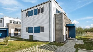 A modern two-story house with a flat roof, white siding, and blue accents.