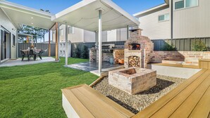 A backyard with a barbecue area, a covered patio, and a well-maintained lawn.