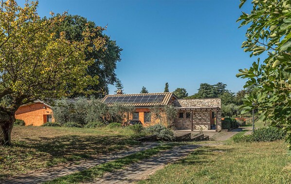Una casa rústica con fachada de piedra, techo con paneles solares y un camino empedrado que lleva a la entrada.