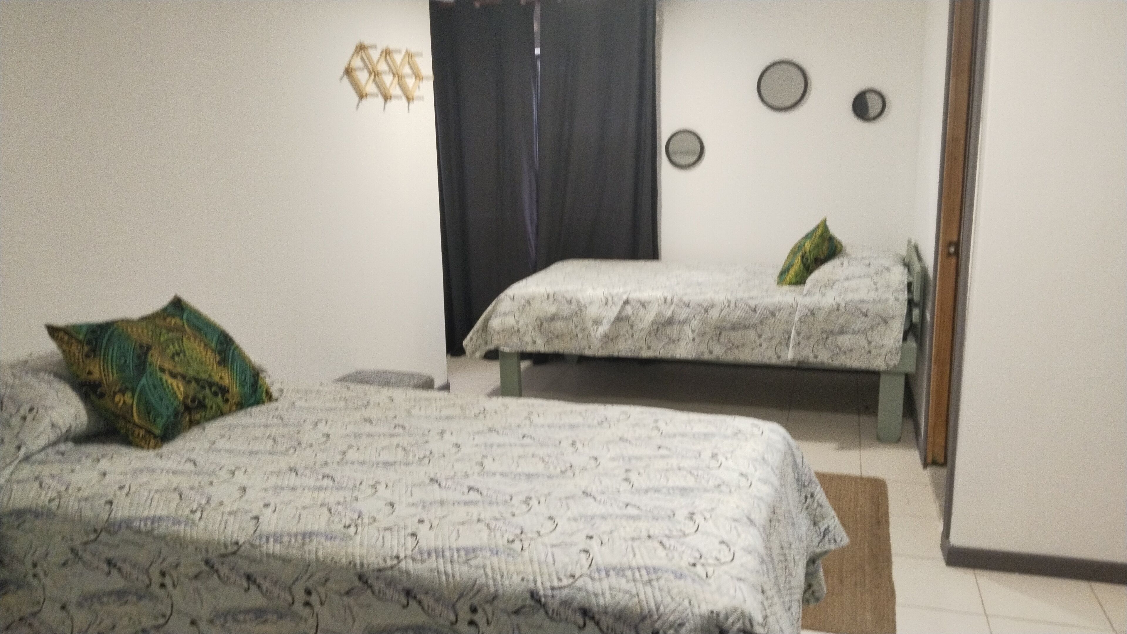 A bedroom with two beds, a black curtain, and a wall-mounted clock.