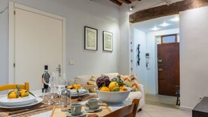 A dining area with a table set for two, a bowl of fruit, wine glasses, and a bottle of wine. - GuestHost - Comfortable apartment of about 50 sqm that can accommodate up to 2 people located on the first floor of an ancient building, without elevator (NOT suitable for the disabled). The property is located in the center of Pisa a short distance from (Pisa)