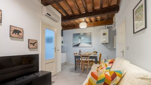 A living room with a TV, a sofa with colorful cushions, a dining area with a table and chairs, and a kitchen with a stove and a framed picture on the wall. - GuestHost - Comfortable apartment of about 50 sqm that can accommodate up to 2 people located on the first floor of an ancient building, without elevator (NOT suitable for the disabled). The property is located in the center of Pisa a short distance from (Pisa)