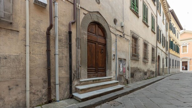 A building with a stone facade, a wooden door, and a set of stone steps leading to the entrance. - GuestHost - Comfortable apartment of about 50 sqm that can accommodate up to 2 people located on the first floor of an ancient building, without elevator (NOT suitable for the disabled). The property is located in the center of Pisa a short distance from (Pisa)