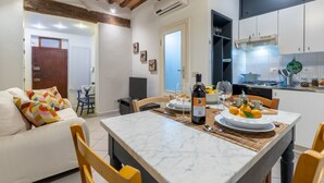 A modern kitchen with white cabinets, a dining table with a bottle of wine, and a fruit bowl. - GuestHost - Comfortable apartment of about 50 sqm that can accommodate up to 2 people located on the first floor of an ancient building, without elevator (NOT suitable for the disabled). The property is located in the center of Pisa a short distance from (Pisa)