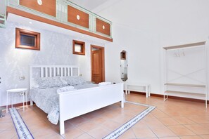 Un dormitorio con cama, mesita de noche, cómoda, espejo y armario.