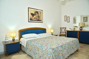 Ein Schlafzimmer mit Bett, Nachttischen, einem Sessel, einem Schminktisch und einem Bild an der Wand.