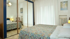 Una camera da letto con un letto grande, un armadio, uno specchio, una luce a soffitto e un quadro appeso al muro.