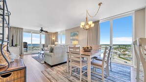 A spacious living area with a dining table, chairs, and a view of the city. - Gulf Views With Direct Beach Access! Terrace At Pelican Beach 1401! (Destin)