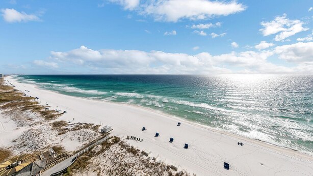 A beach with a clear sky, calm sea, and a sandy shore with beach chairs and umbrellas. - Gulf Views With Direct Beach Access! Terrace At Pelican Beach 1401! (Destin)