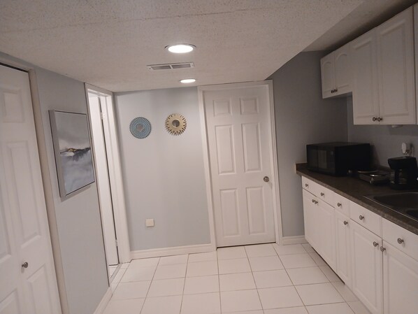 A kitchen with white cabinets, a microwave, and a coffee maker on the counter.