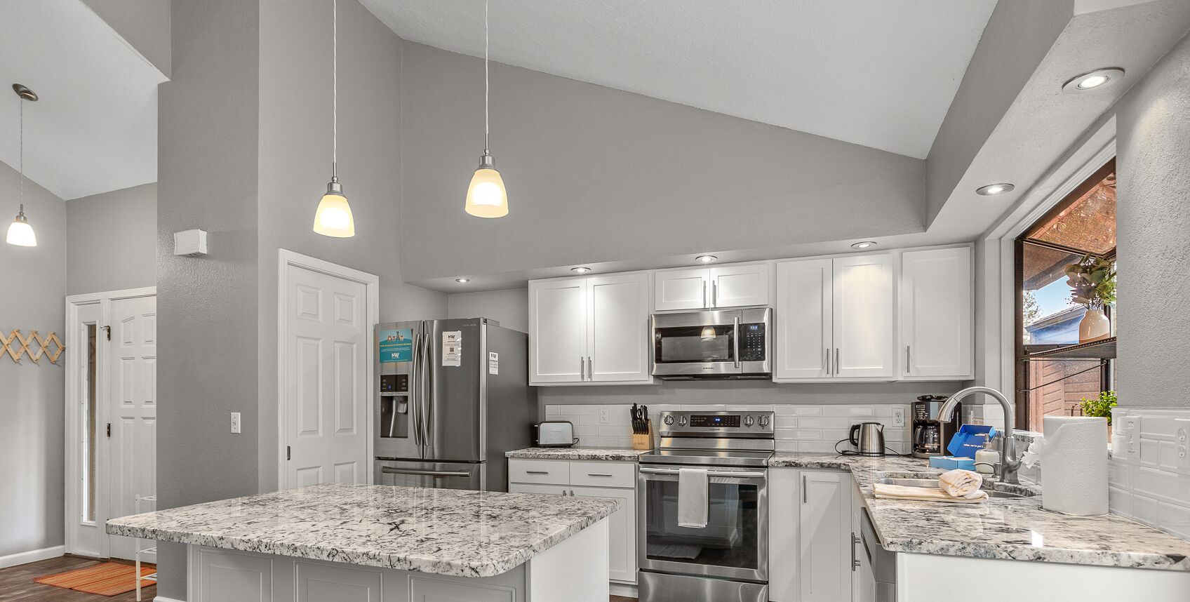 A modern kitchen with white cabinets, stainless steel appliances, and a granite countertop.