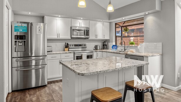A modern kitchen with stainless steel appliances, a granite island, and pendant lighting. - Twin Lakes Village Home—Golf Retreat, Community Pool, Corner Lot, and Single-Level Living! (Rathdrum)