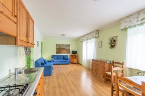 Un espacio habitable compacto con cocina, un sofá azul, armarios de madera y una zona de comedor.