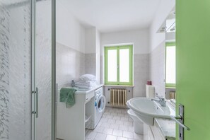 Un baño moderno con lavadora, radiador y un lavamanos grande.