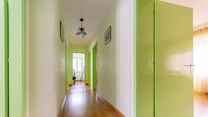 A hallway with green doors and a wooden floor. - Casa Iris 2 (Falcade)